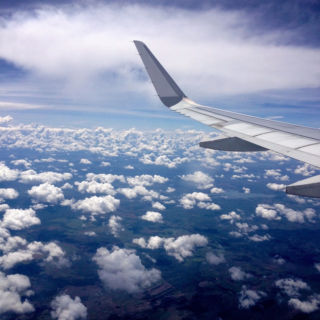 The wing of an airplane flying above the clouds. Blue sky sky of