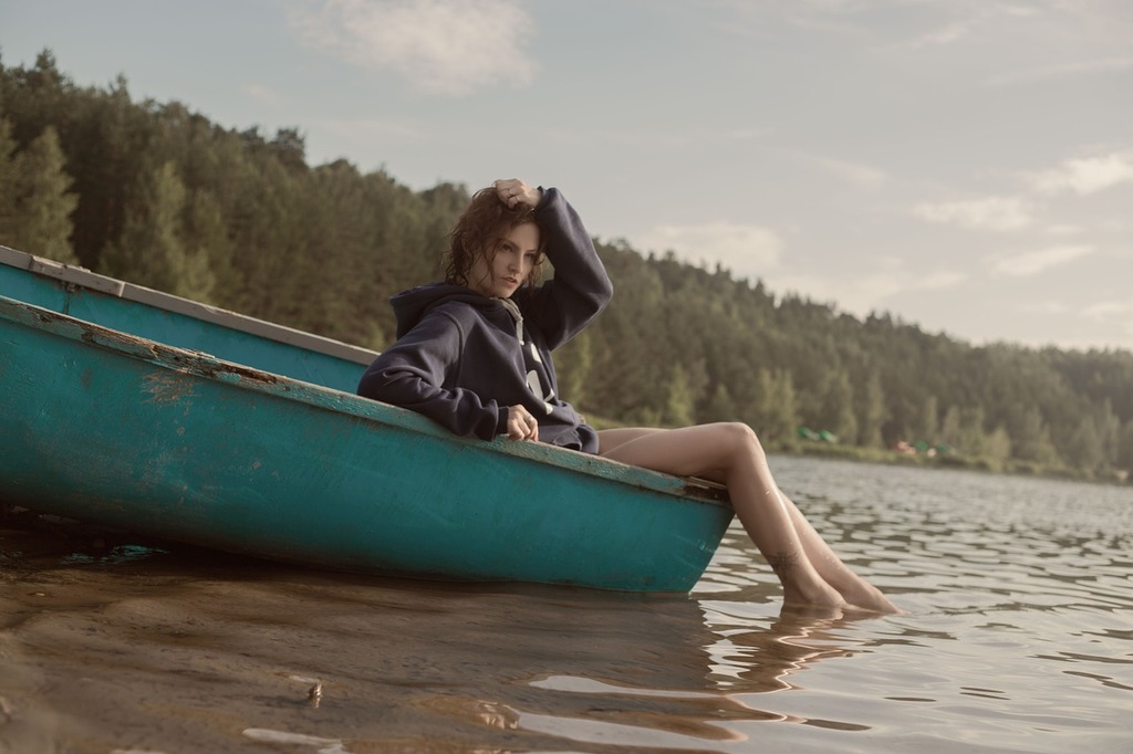 A woman sitting in a blue boat on a lake. Boat river girl, people