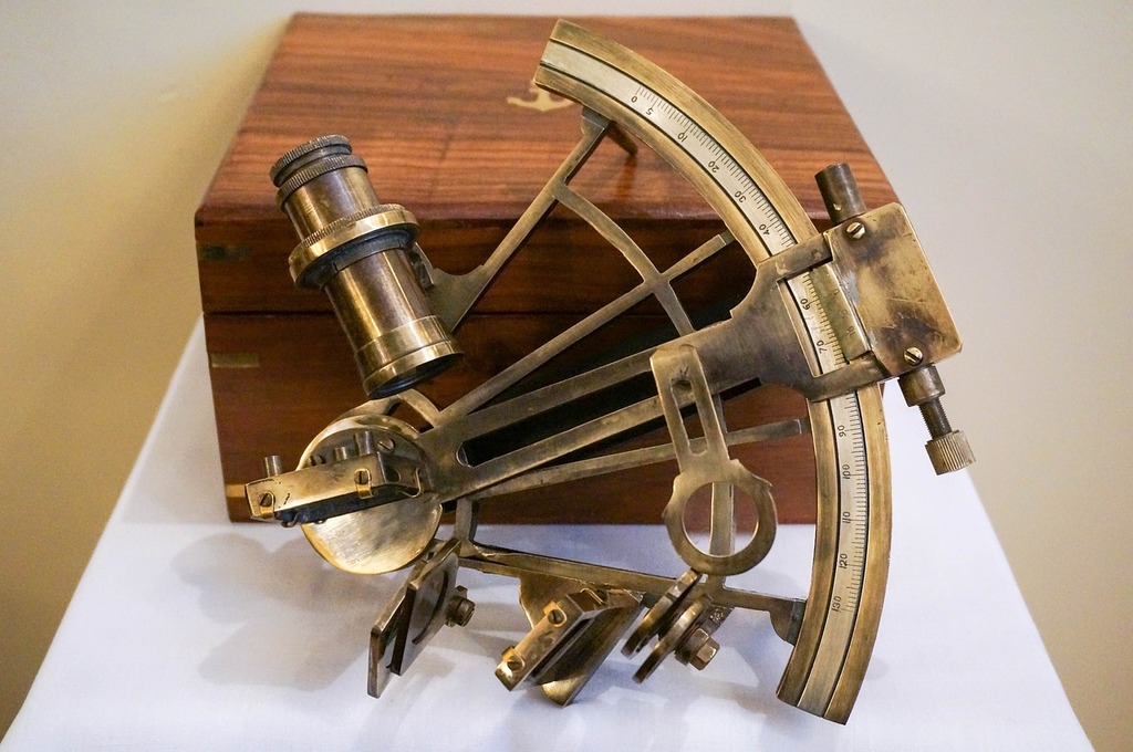 A brass sexet on a white table. Brass nautical sextant captain