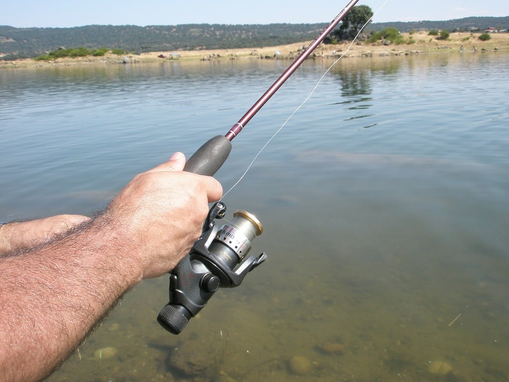 A man holding a fishing rod in the water. Cane of fishing