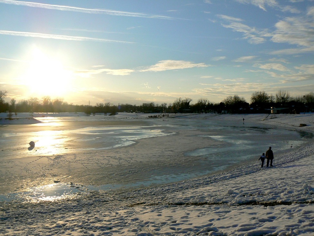 A group of people walking across a snow covered field. Frozen lake