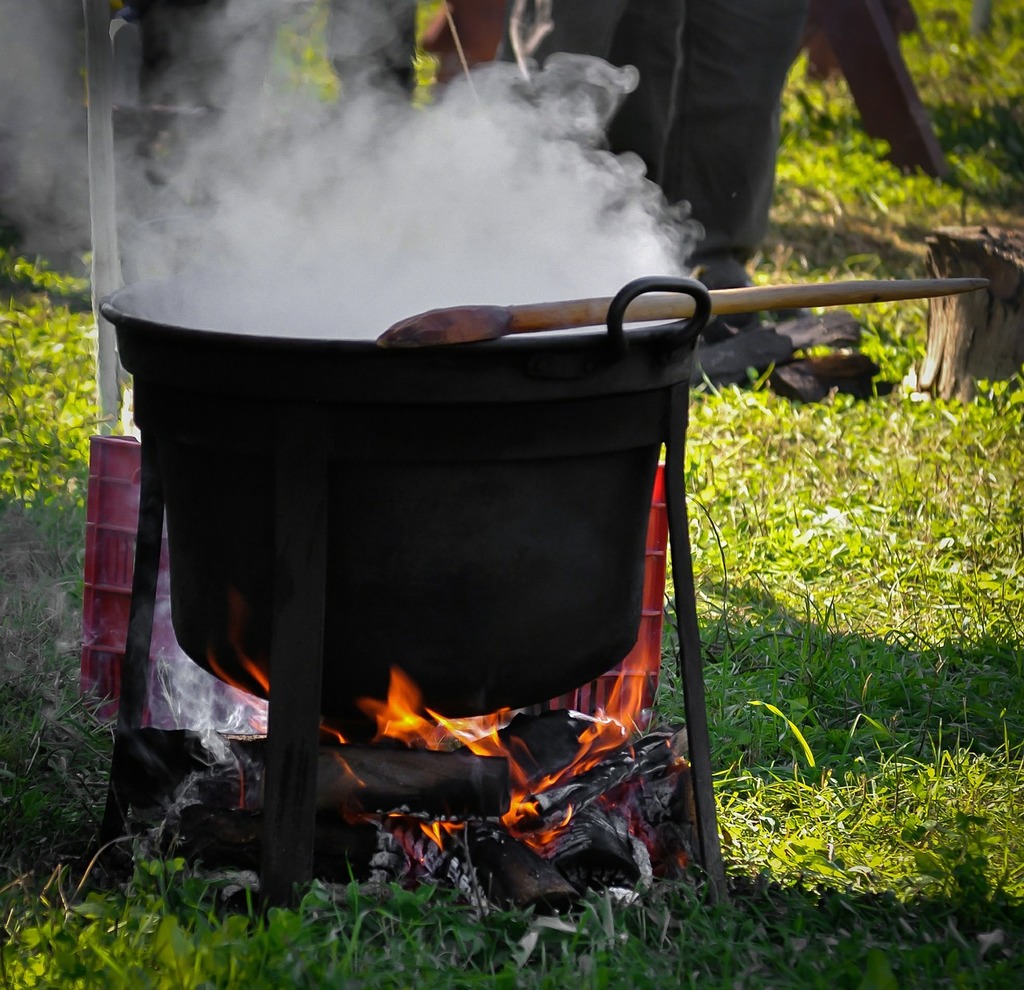 A large pot on a fire with smoke coming out of it. Kettle cauldron