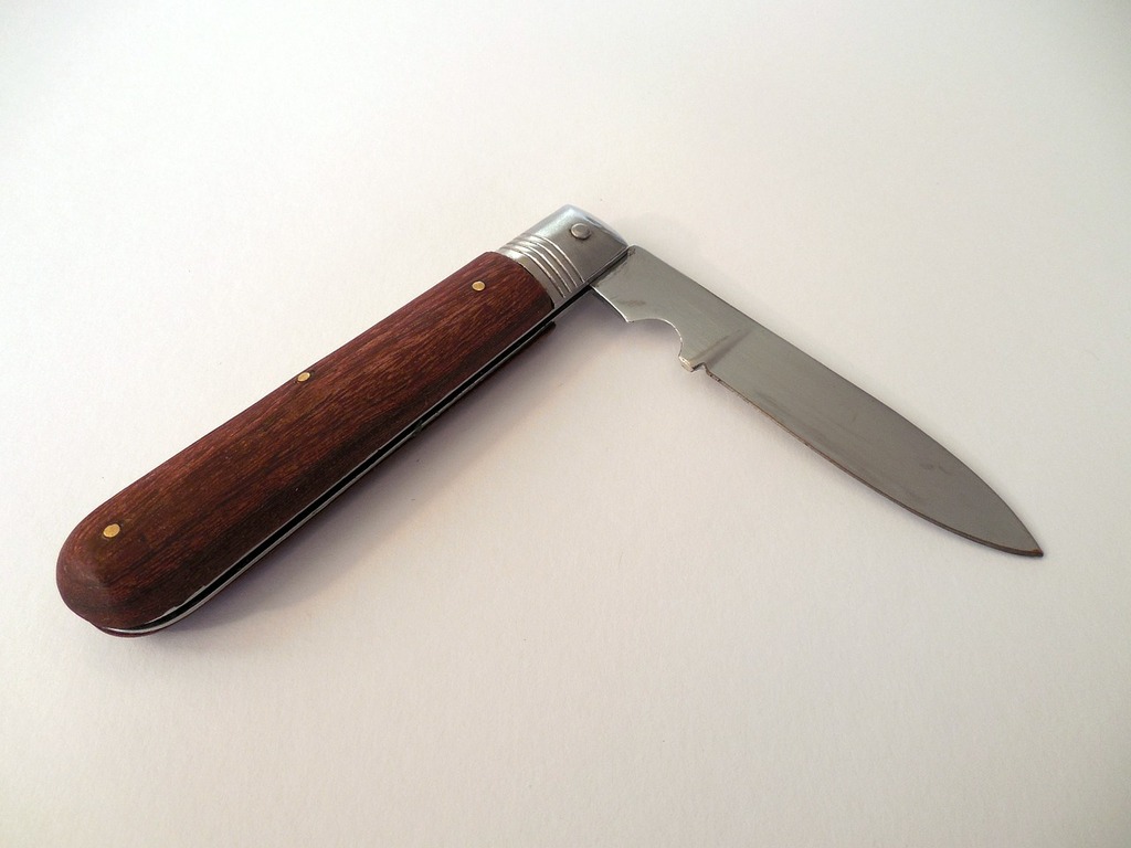 A knife with a wooden handle on a white surface. Knife pocket