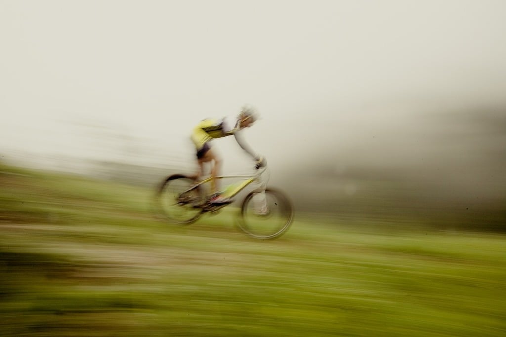 A blurry photo of a person riding a bike. Mountain bike downhill