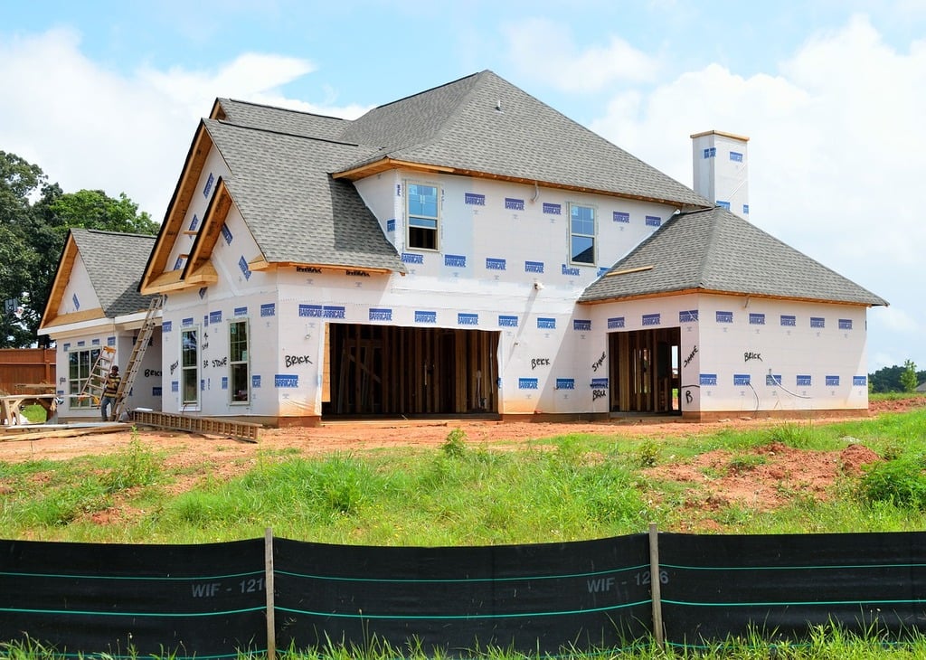 A house under construction with a fence in front of it. New home  construction build building. - Crosley Family Moving