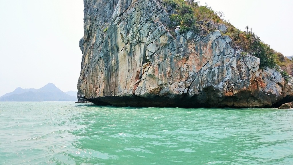 A large rock in the middle of a body of water. Ocean rock water