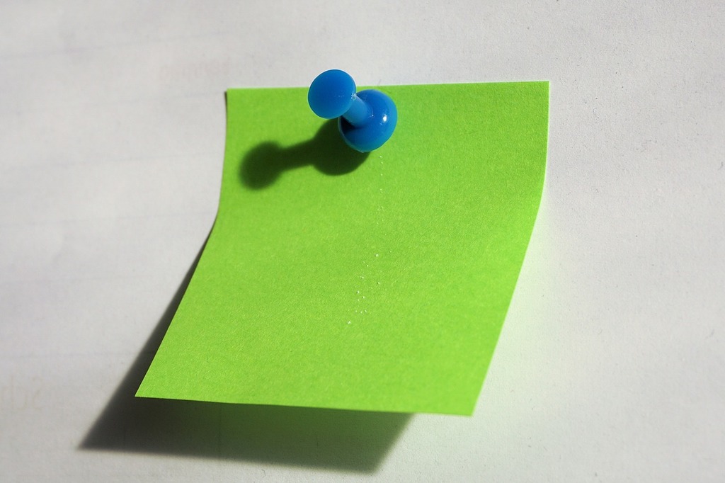 A light green sticky note attached to a map pin, suitable for