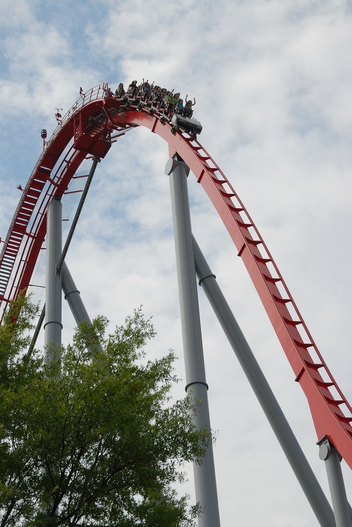 A red roller coaster going up a hill. Roller coaster ride amusement