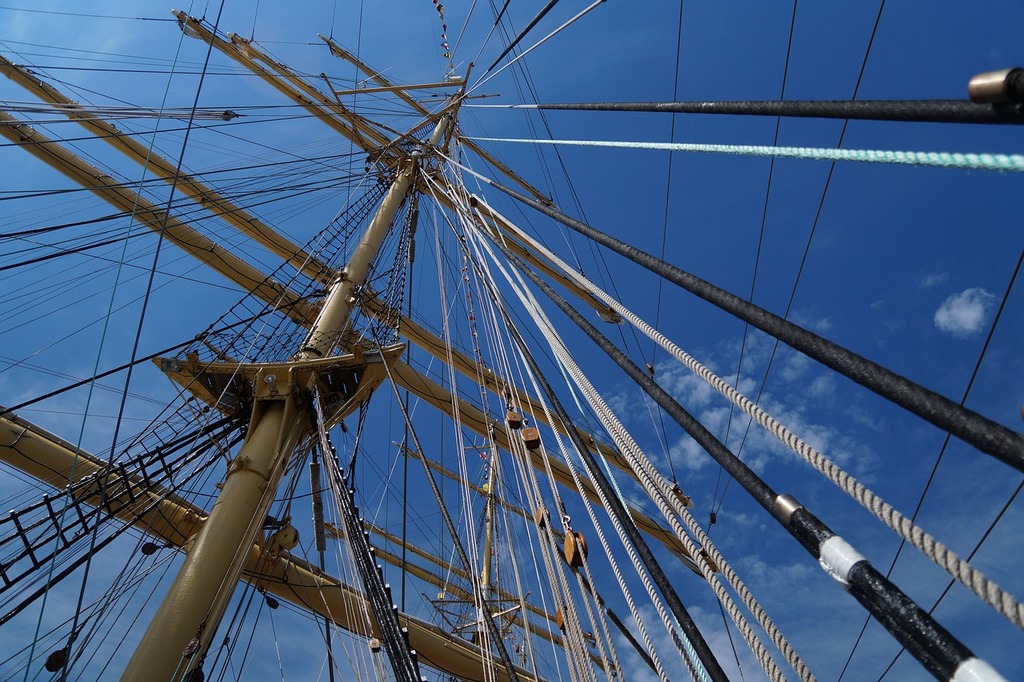 A tall mast with ropes and ropes on it. Sailboat ropes rope