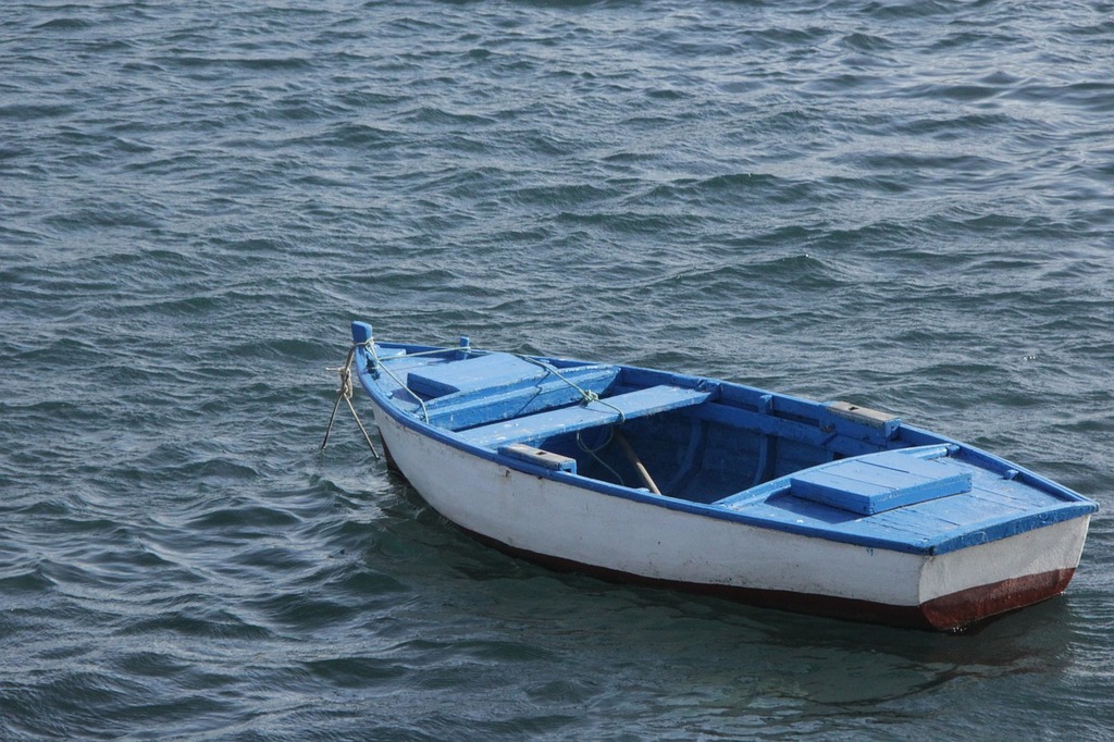 A small boat floating on top of a body of water. Sea little boat