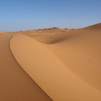 A desert with sand dunes and a clear blue sky. Sahara desert sand